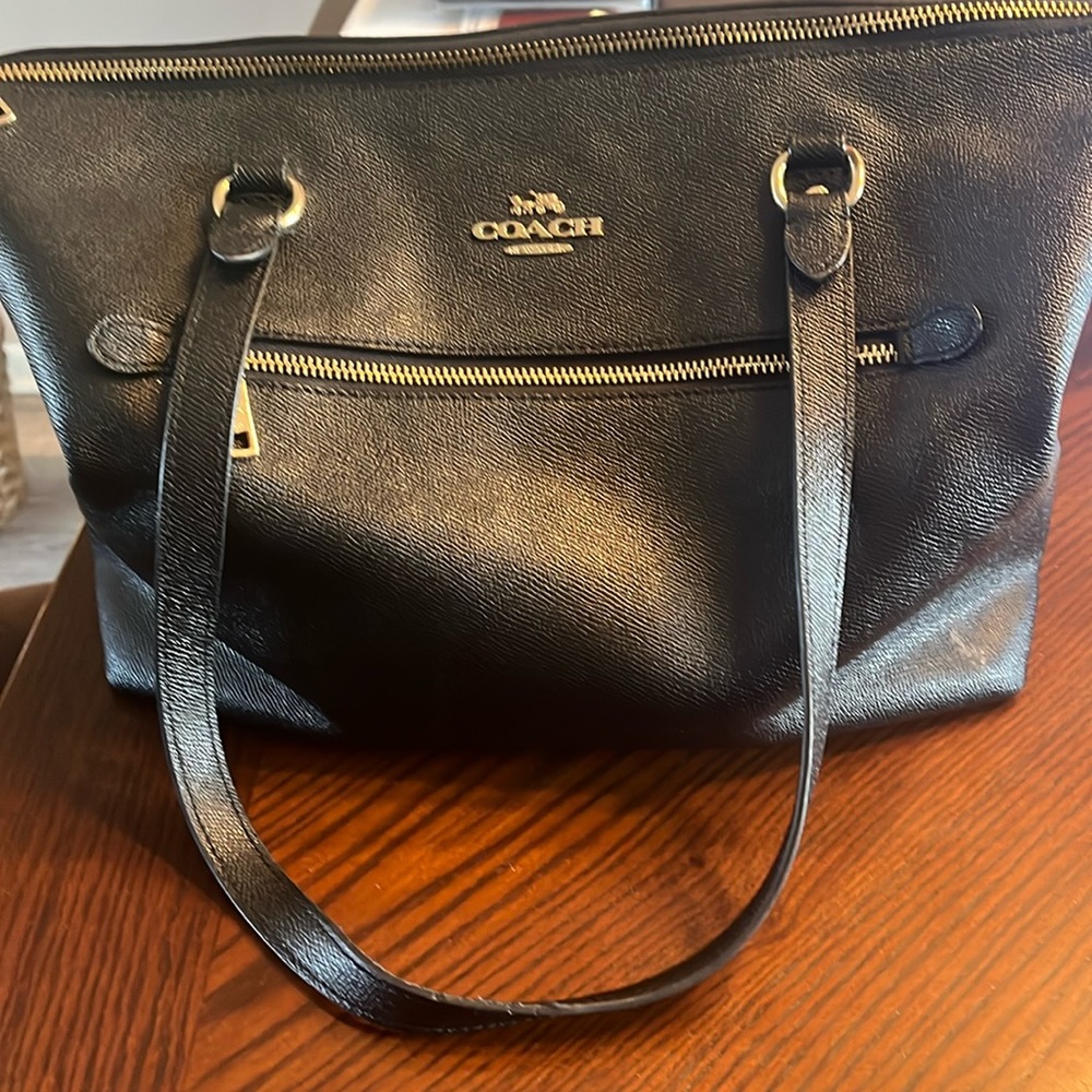 Black coach tote purse with gold zippers.